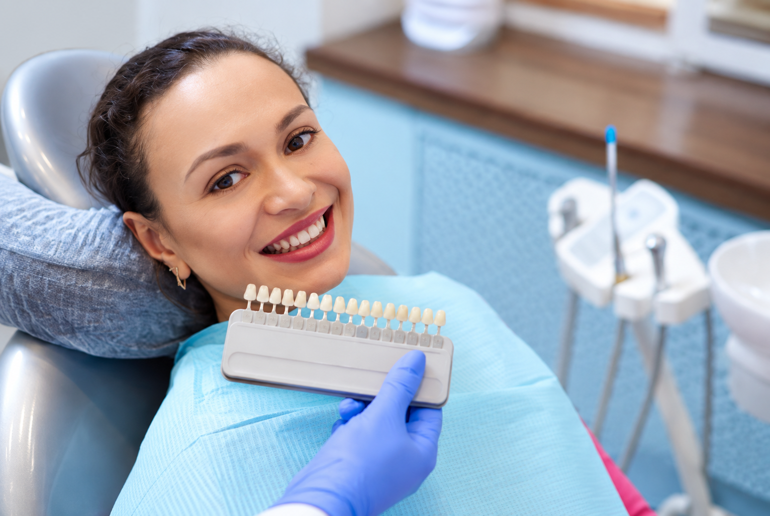 Woman smiling at dentist holding teeth shade guide