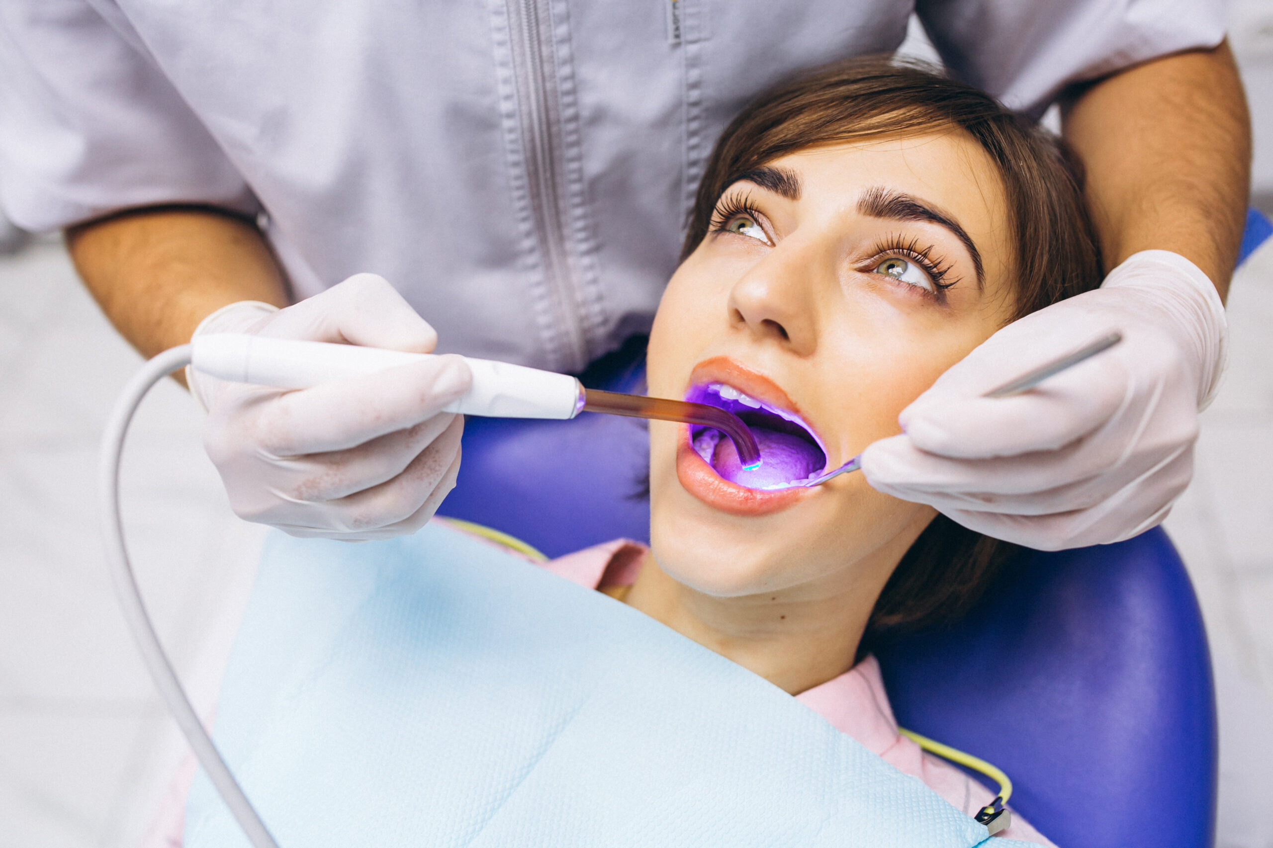 Dentist using UV light on patient's teeth for composite bonding.